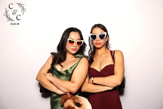Two women wear heart-shaped sunglasses and cross their arms in a confident