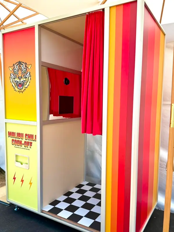 Aviator Nation custom Enclosed Vintage Booth with colorful panels, red curtain, and checkered floor.
