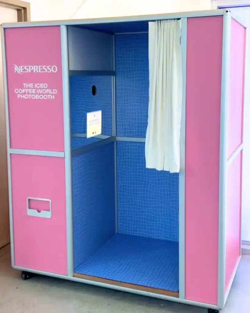 Nespresso branded Enclosed Vintage Booth with pink exterior, blue interior, and white curtain.