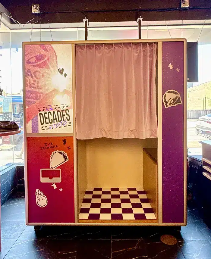 Taco Bell branded Enclosed Vintage Booth with custom panels, pink curtain, and checkered floor.