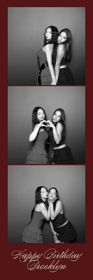 Two women pose back-to-back, make a heart, and blow kisses in a black-and-white Glam Photo Booth birthday strip.