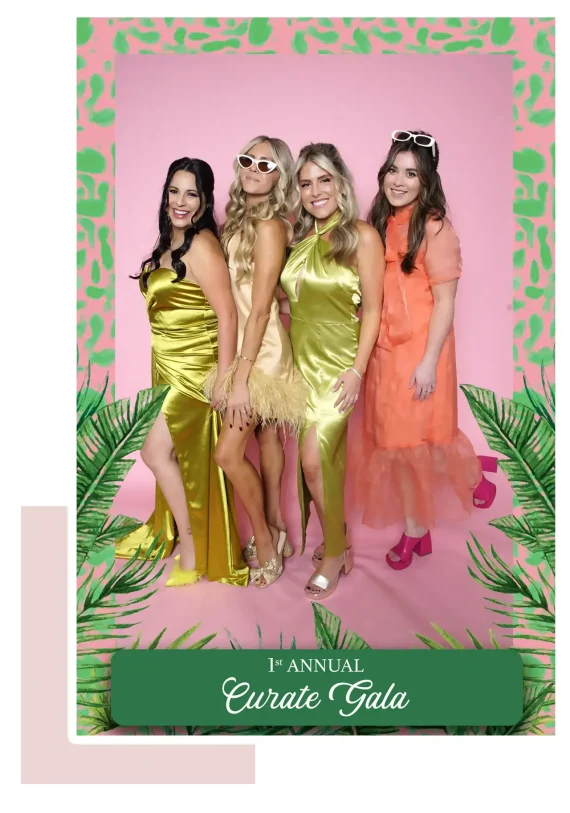 Four stylish ladies posing in a rented photo booth, dressed in elegant gowns at the Curate Gala event.